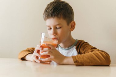 boy sitting at the table and drinking orange juice