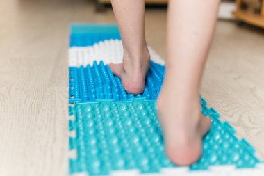 a boy walks on an orthopedic rug
