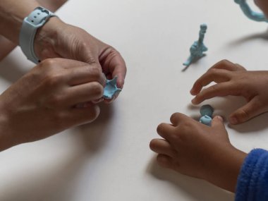 Çocuk ve anne renkli dinozor kil figürleriyle oynuyorlar..