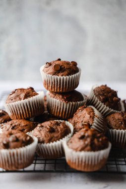 Close up of many chocolate chip zucchini muffins on white background.