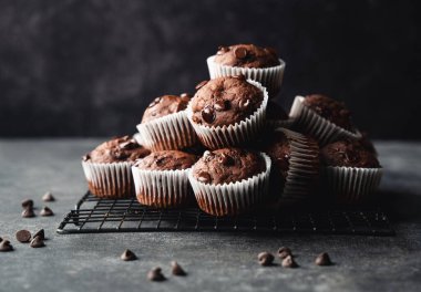 Close up of many chocolate chip zucchini muffins on black background.