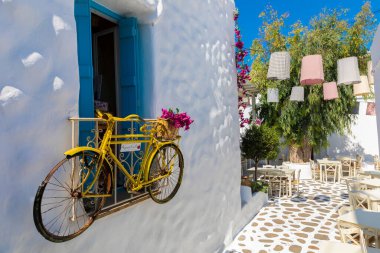 Yunanistan 'ın Naxos Adası' ndaki sıva binasında sarı bir bisiklet asılı duruyor