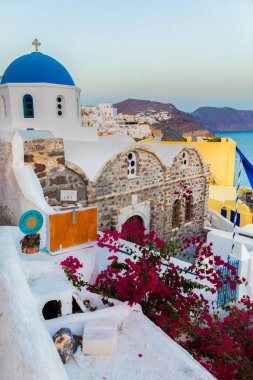 Santorini 'deki Fira köyünde mavi kubbeli kilise ve begonviller.