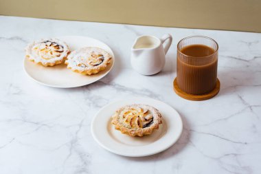 dessert on a plate and coffee with milk in a glass.