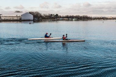 Nehirde büyük bir bacaya karşı kürek çeken iki kanocu.