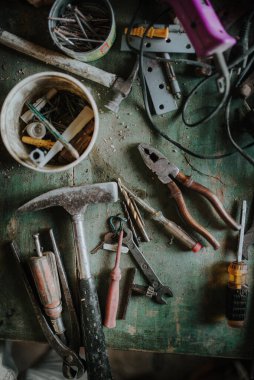 Old and broken tools on green wooden table. Top view.
