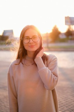 The wind blows the hair of a young woman at sunset