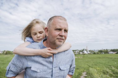 Kızı onu sırtında taşıyan babasını kucaklıyor..