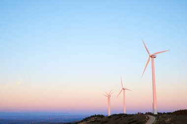 Wind turbines generators for renewable electric energy production illuminated with twilight light