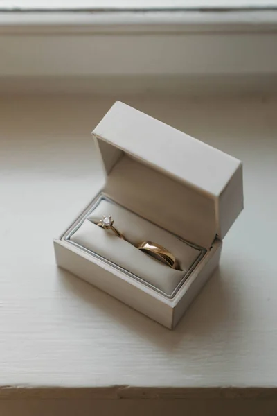 白い木製の表面に白いリングボックス内の黄金の結婚指輪 — ストック写真