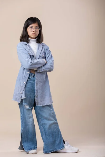 full shot of Mexican young girl arms crossed serious face. blue jeans