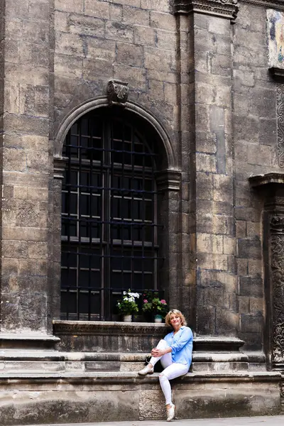 Young Blond Woman Sits Background Gothic Facade — Stockfoto