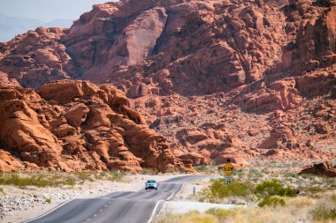Winding road in the desert with reddish mountains in the bkgrnd