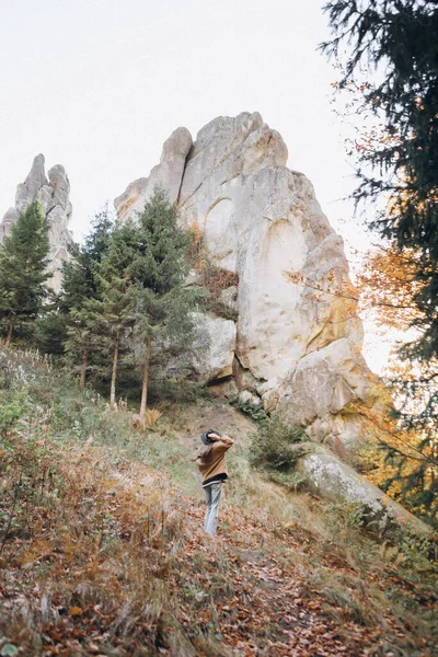 身穿夹克头戴帽子的女人穿过山边的树林 — 图库照片