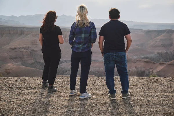 三个人从一个角度来看大峡谷 风很大 — 图库照片