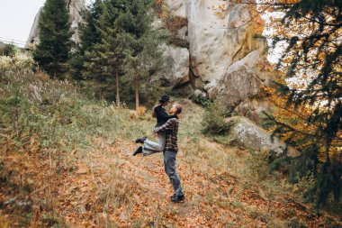 Erkek ve kadın, dağların arka planında sarılırlar.