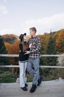 Erkek ve kadın, dağların arka planında sarılırlar.