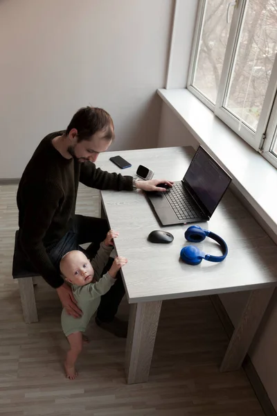 子供と一緒に自宅でラップトップで作業している若い男 — ストック写真