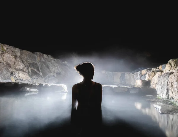 在自然温泉里的女人 晚上用蒸汽和背光 — 图库照片