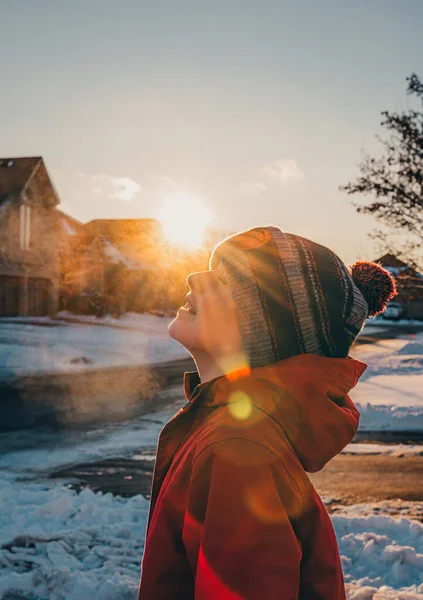 在阳光明媚的冬日 戴着冬帽和外套的男孩呼出了寒冷的空气 — 图库照片