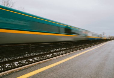 Blurred fast moving passenger train travelling down the tracks.