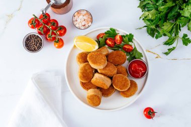 chicken nuggets in a plate on a light background, tomato sauce,