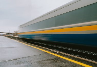 Blurred fast moving passenger train travelling down the tracks.