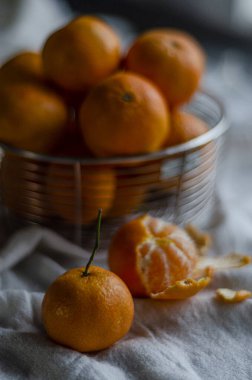 tangerine with a sprig but background with a basket of fruits