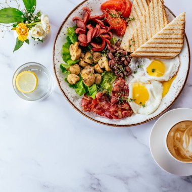english breakfast with scrambled eggs, bacon, beans, mushrooms and coffee on a marble table