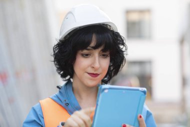 Dışarıda çalışan miğferli genç mühendis kadın.