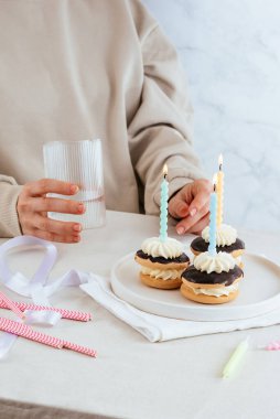 born with candles, a girl holds a glass with a drink in the background