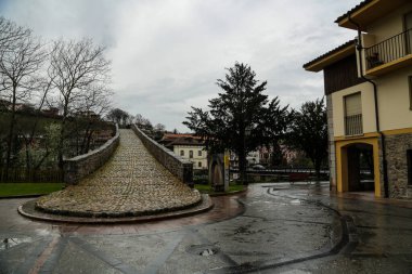 Stone bridge with houses with yellow facades and various trees