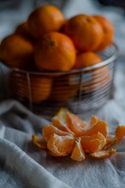 peeled tangerine on a light tablecloth next to the basket
