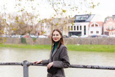 Yünlü ceketli bir kadın bahar şehrinin ortasında tek başına yürüyor.