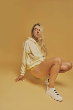 Young freckles woman wearing a yellow sweatshirt over yellow