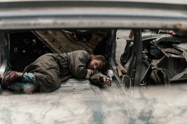 a homeless man sleeps in a car dump