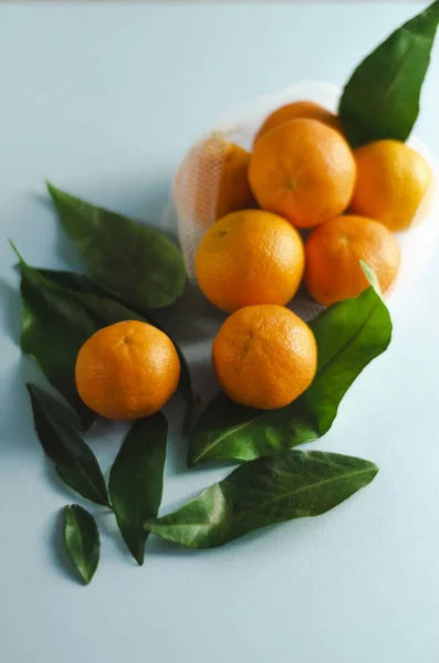 tangerines in an eco-bag and scattered near with leaves