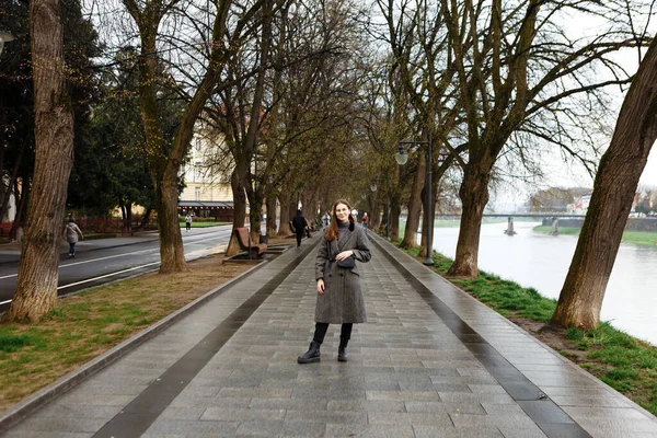 ウールのコートを着た女性が春の街の真ん中を一人で歩き — ストック写真