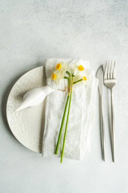 Spring table setting with daffodil flowers on concrete background
