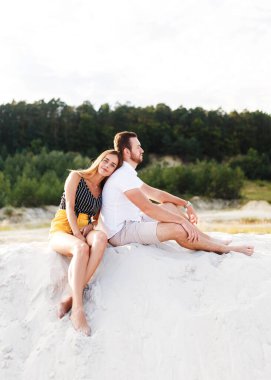 young couple in love are sitting on a sandy beach on vacation