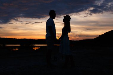 Couple standing holding hands at summer sunset