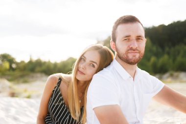 couple in love laughing sitting on sandy beach on vacation