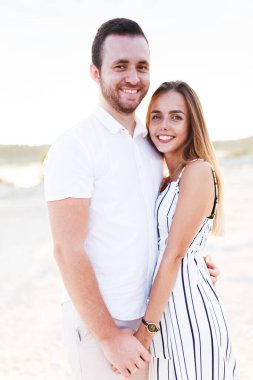 man and a woman are hugging on a sandy beach in summer