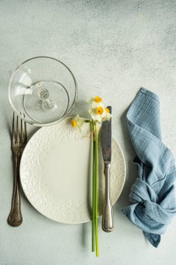 Spring table setting with daffodil flowers on concrete background