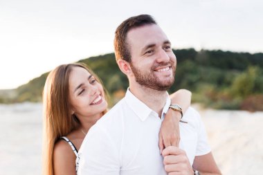 man and a woman are hugging on a sandy beach in summer