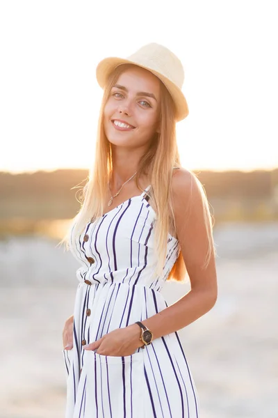 年轻的金发姑娘戴着帽子 穿着夏装在海滩上 — 图库照片