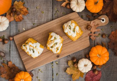 Ahşap masadaki sonbahar dekorlu balkabağı çörekleri..