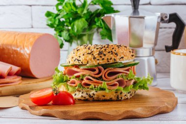 Jambonlu ve otlu simit. Jambon yakında. Kahve. Kahvaltı.