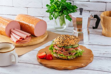 Jambonlu ve otlu simit. Jambon yakında. Kahve. Kahvaltı.