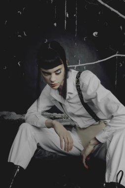 Siyah duvarın yanında Kubrick tarzı esmer bir model poz veriyor.